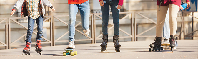 Four children playing on rollerblades and a skateboard.