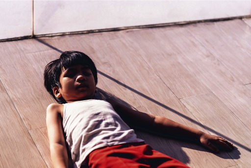 Photograph of a young boy lying on the ground