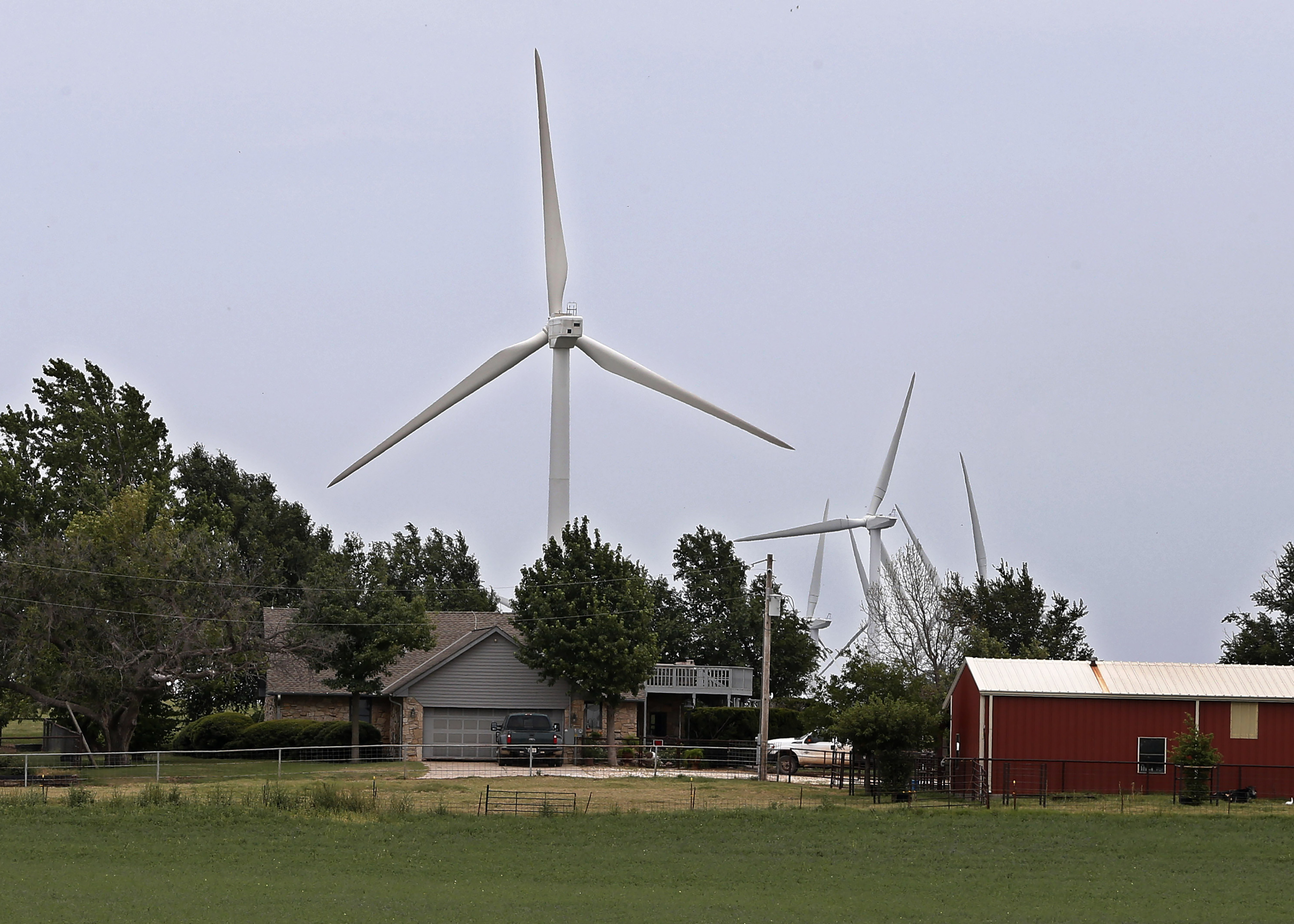 House and barn with large windmills rising behind them