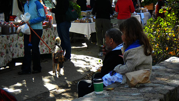 Man sitting outdoors smoking a cigarette while a child behind him covers her mouth and nose.