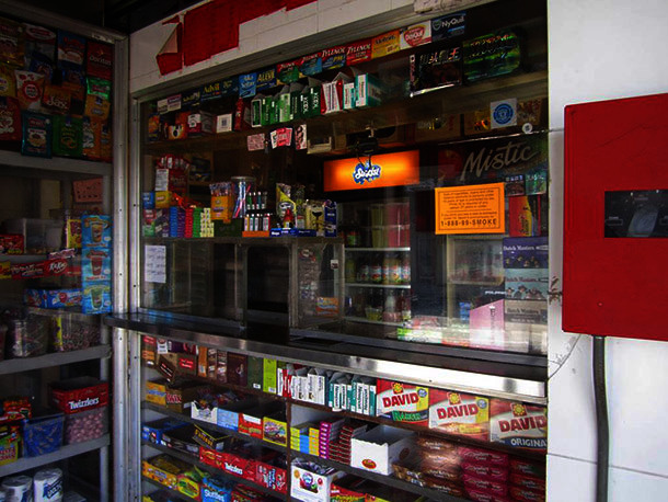 A convenience store counter and shelf display of candy and cigarettes.