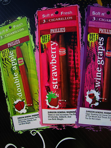 Part of a sign showing colorful packages of cigarillos with apple, strawberry, and grape flavorings.