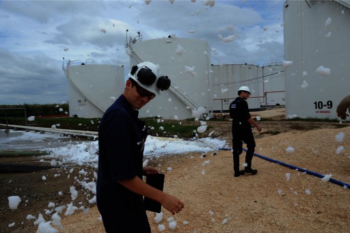 Photograph of U.S. Coast Guard personnel walking through wind-blown foam at the Kinder Morgan spill site