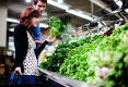 Photograph of a young couple shopping for produce.