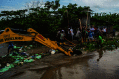 People and machinery clearing debris from flooded canal