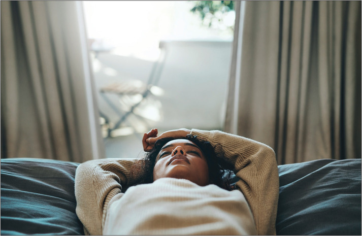 Cropped shot of a young woman lying on her bed with her eyes closed