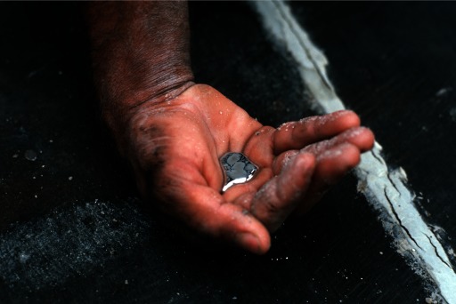 Photograph of a miner's hand holding a palmful of elemental mercury