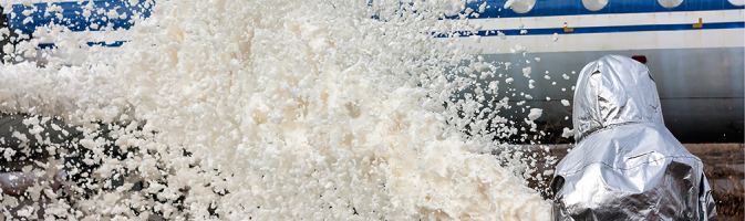 A firefighter spraying foam at a jet