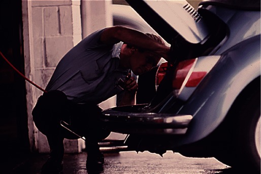 Archival photograph of a mechanic repairing a car