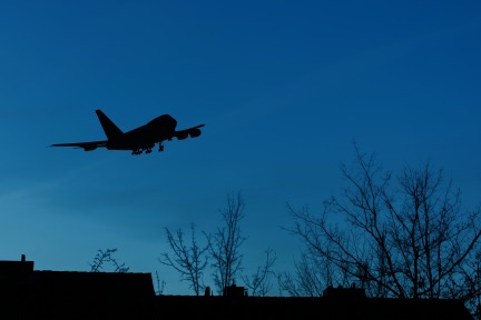 Photograph of an airplane flying over a residential area