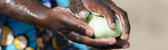 An African girl washing her hands at an outdoor tap