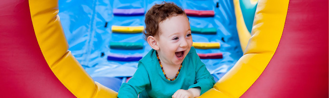 Photograph of a toddler happily playing in an indoor play setting