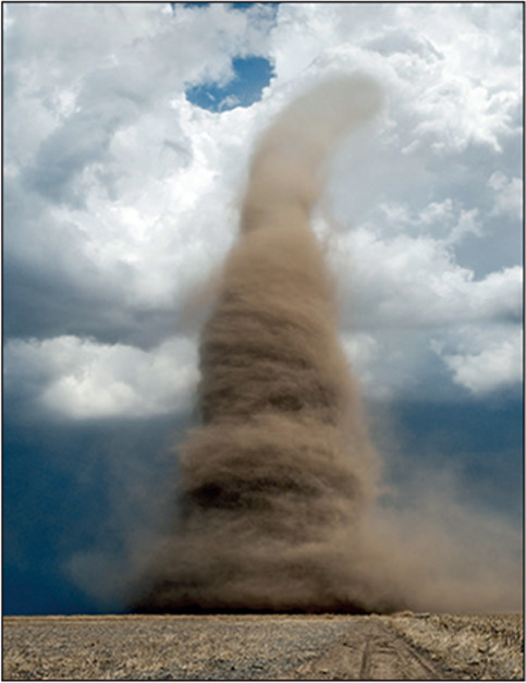 Landspout tornado with a debris cloud, crossing a farm field. This rare, close-range photo, taken within 45 metres of the tornado, shows the violently spinning vortex. In the background is the cloud (white), from which the tornado formed. A tornado is a violent rotating column of air that can form during the growth of a cumulonimbus (thunderstorm cloud). Landspout tornadoes are small, relatively weak tornadoes associated with less severe thunderstorm clouds. They are so-called because they resemble waterspouts, but occur on land. Tornadoes are most common in the mid-west USA. Photographed in May, in western Kansas, USA.