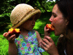 Young girl feeding her mother a peach