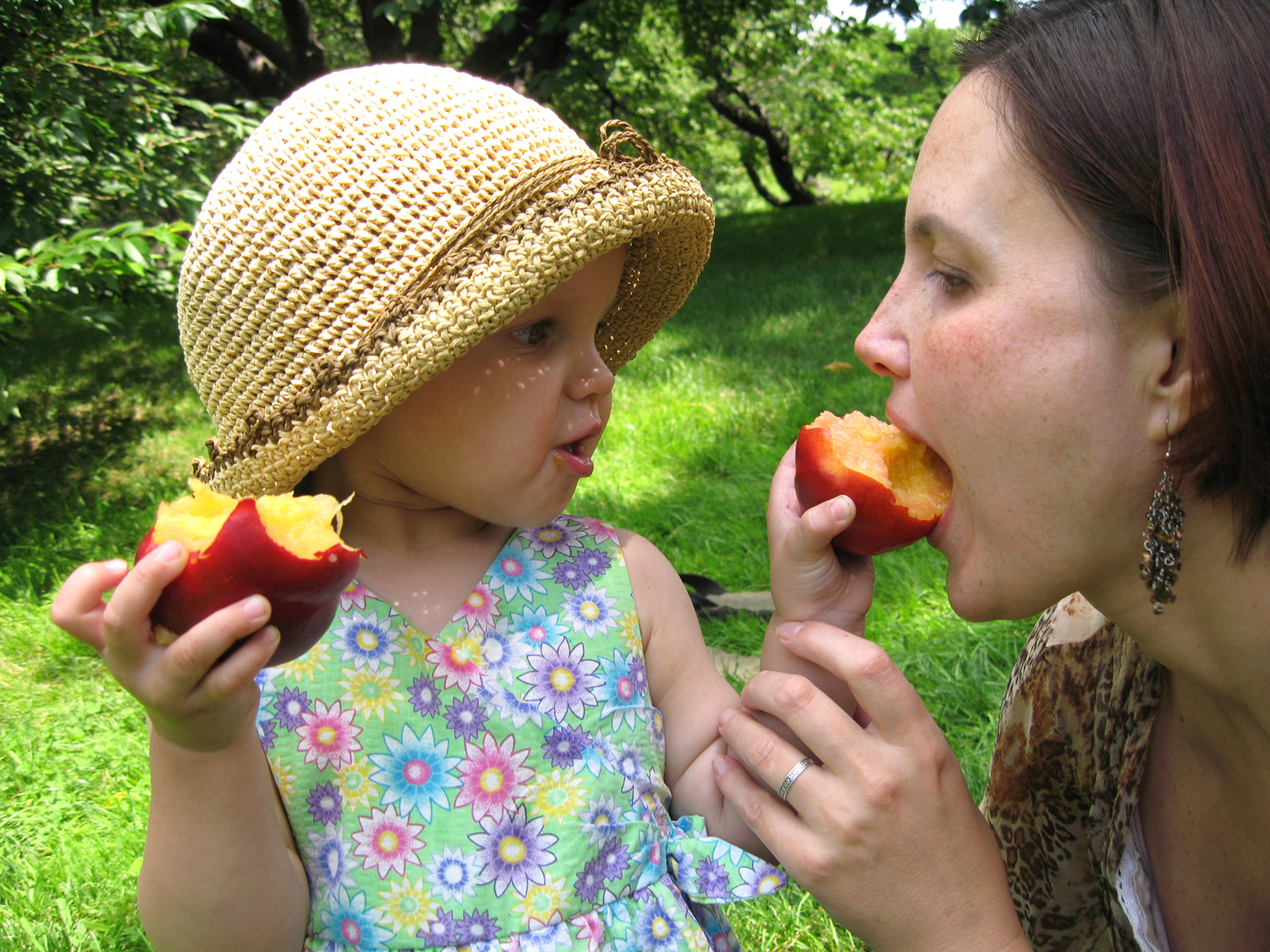 Young girl feeding her mother a peach