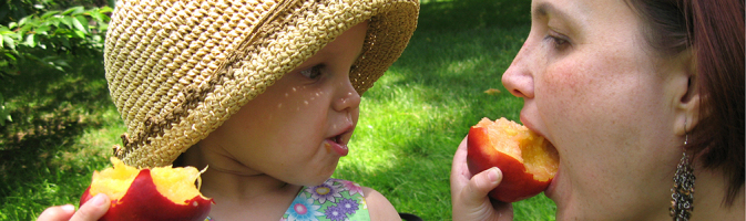 Young girl feeding her mother a peach