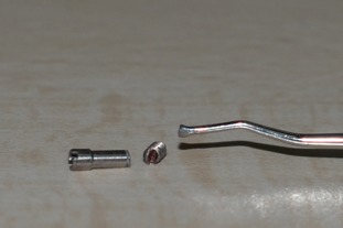 Fig. 2: Retrieved fractured abutment screw and the modified end of the spoon excavator used for the procedure.