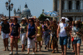 Photograph of a group of tourists crossing a paved plaza in the heat.