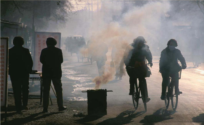 Coal catastrophe. Cyclists on their way to work in Guizhou Province, China, pass through smoke pouring out of a coal-burning cooking stove. Exposure to the arsenic-rich coal burned in this region has resulted in endemic arsenicosis.