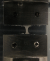 Dog-bone-shape strip placed between customized clamps