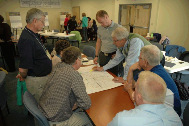 The photograph depicts participants conducting a workshop mapping exercise.