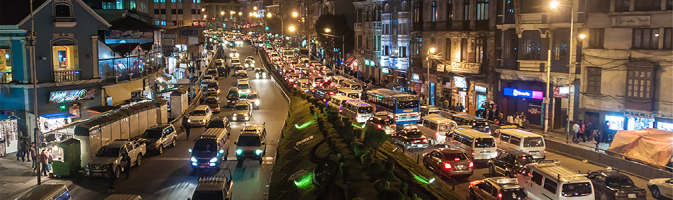 Traffic at night on a street lined by small apartment buildings and houses