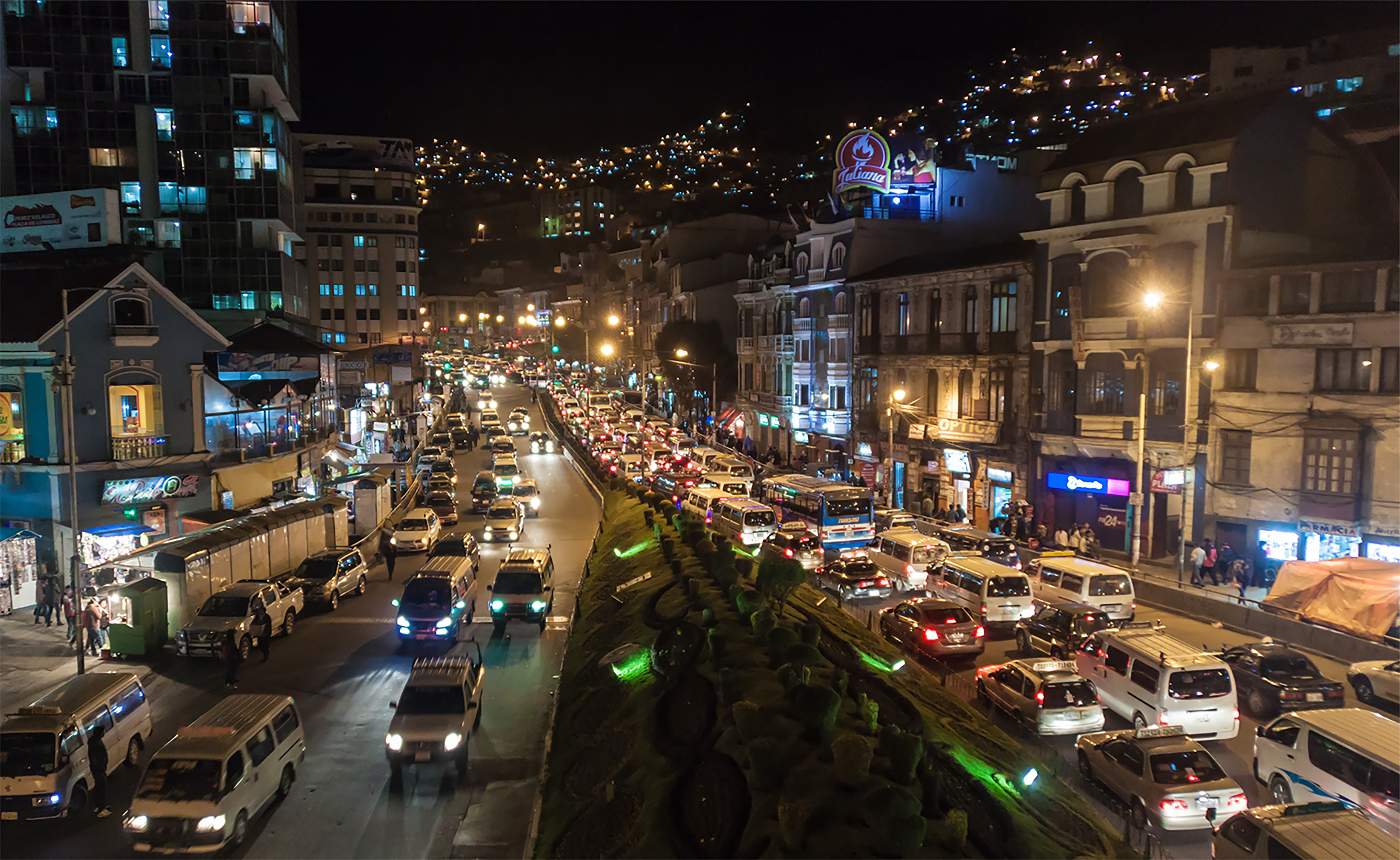 Traffic at night on a street lined by small apartment buildings and houses