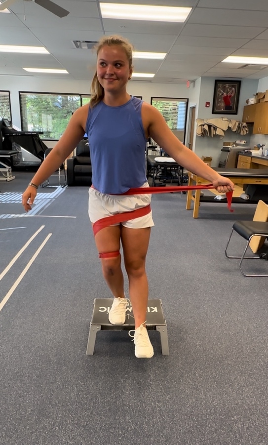 A person standing on a step with a red tape around her waist Description automatically generated