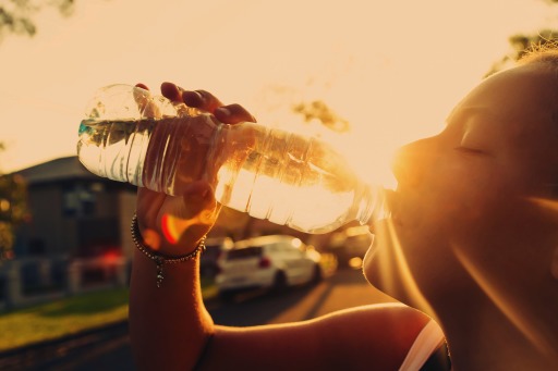 Photograph of a woman drinking from a water bottle on a hot afternoon
