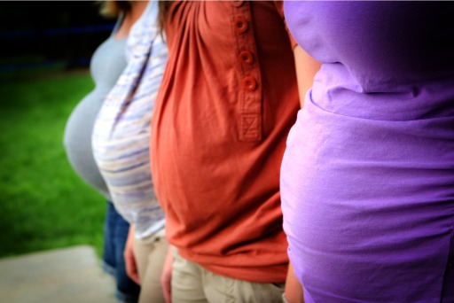 Photograph of four women in different trimesters of pregnancy, standing side by side